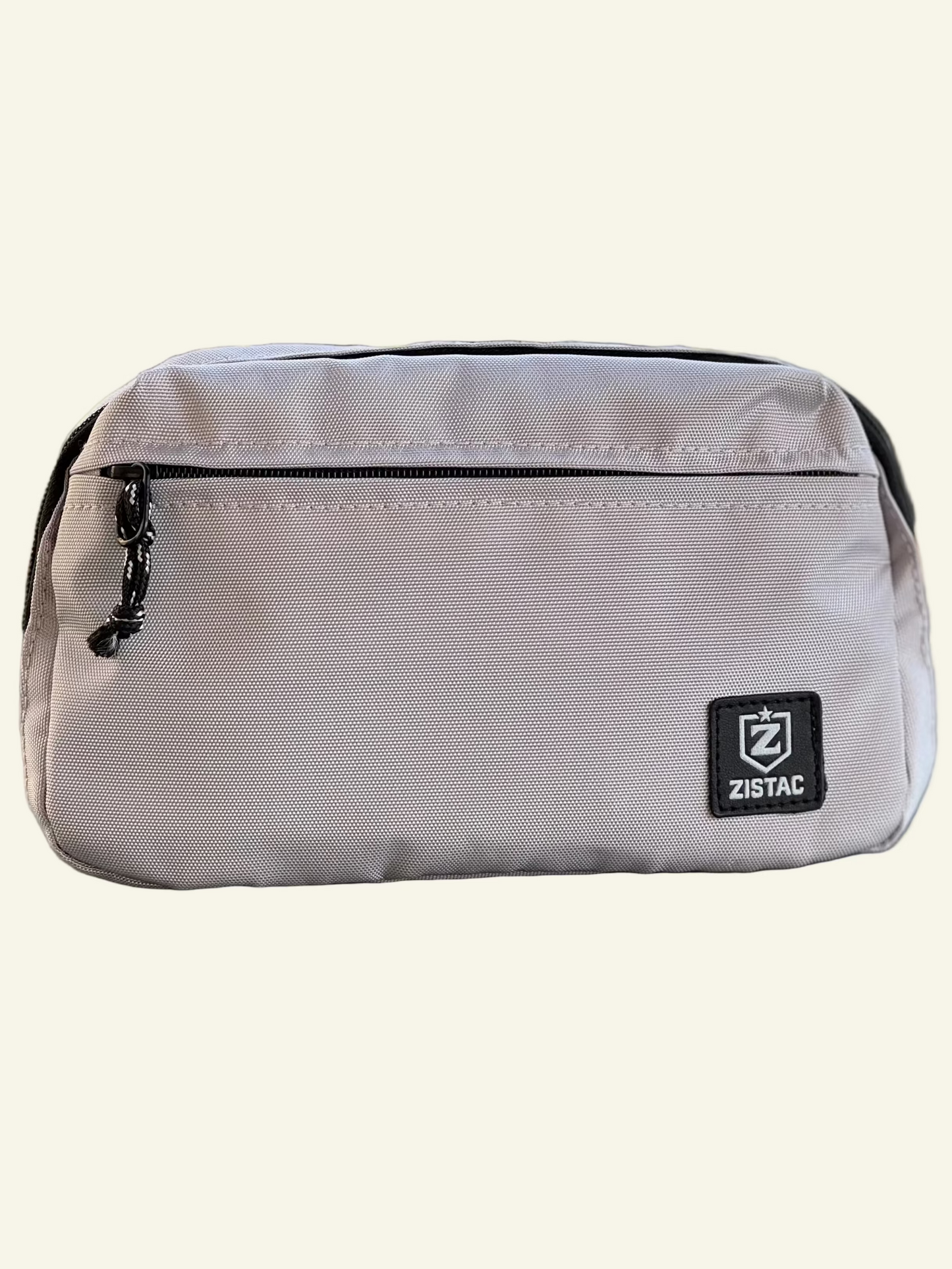 Small beige pouch with a ZISTAC logo on a reflective surface with a blurred green background