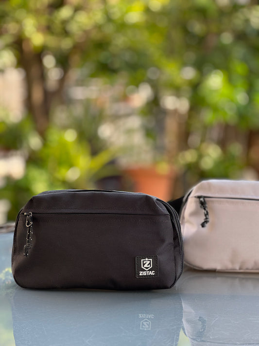 Black and beige bags with a brand logo on a reflective surface with a blurred green background