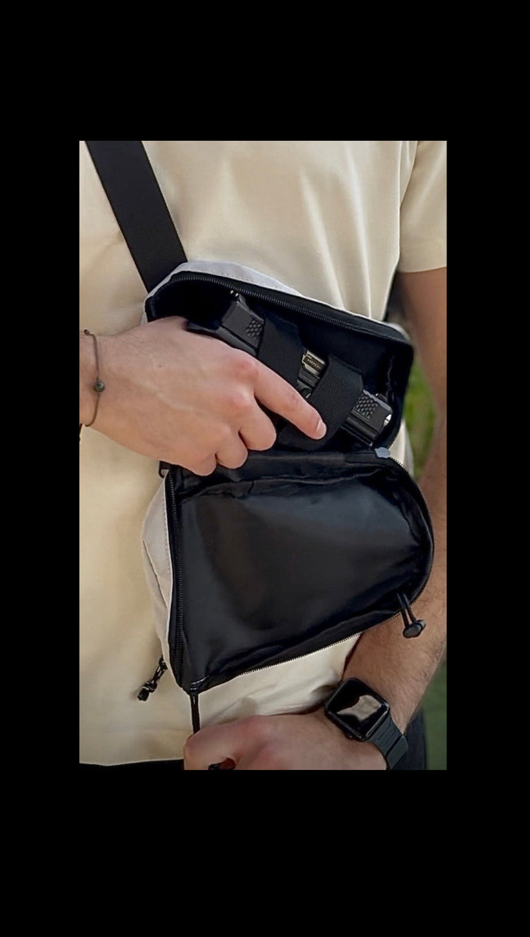 Person holding a black crossbody bag outdoors